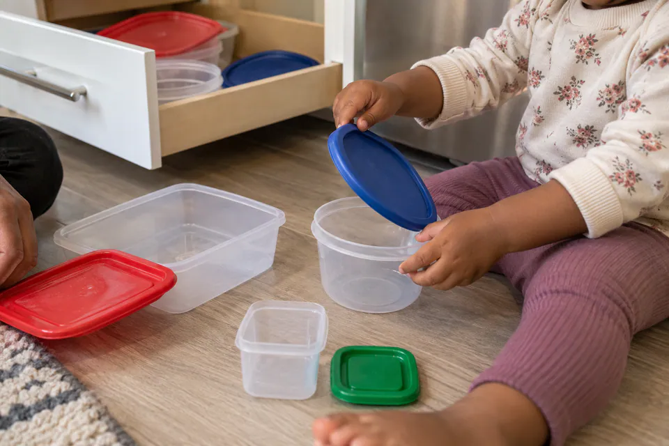 A child matching a blue lid to a plastic food container.