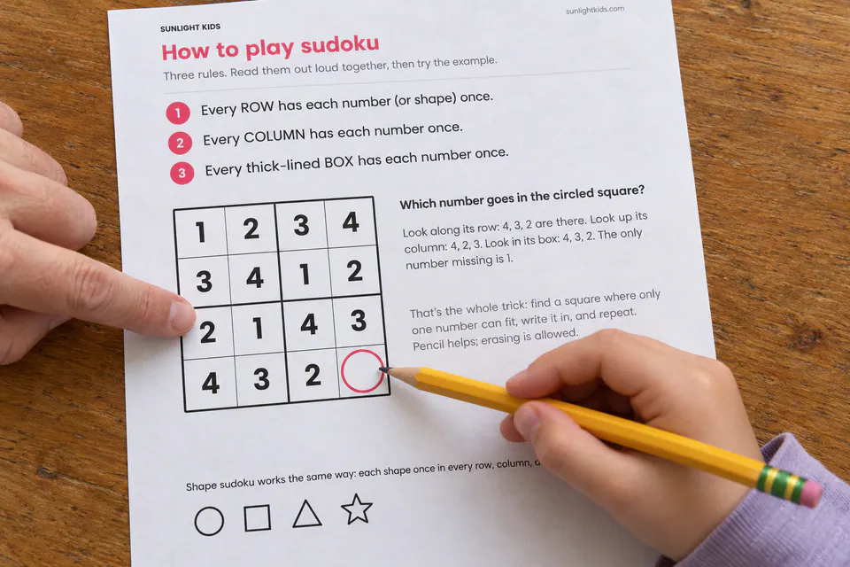 A child and adult using the printed four-by-four sudoku instructions.