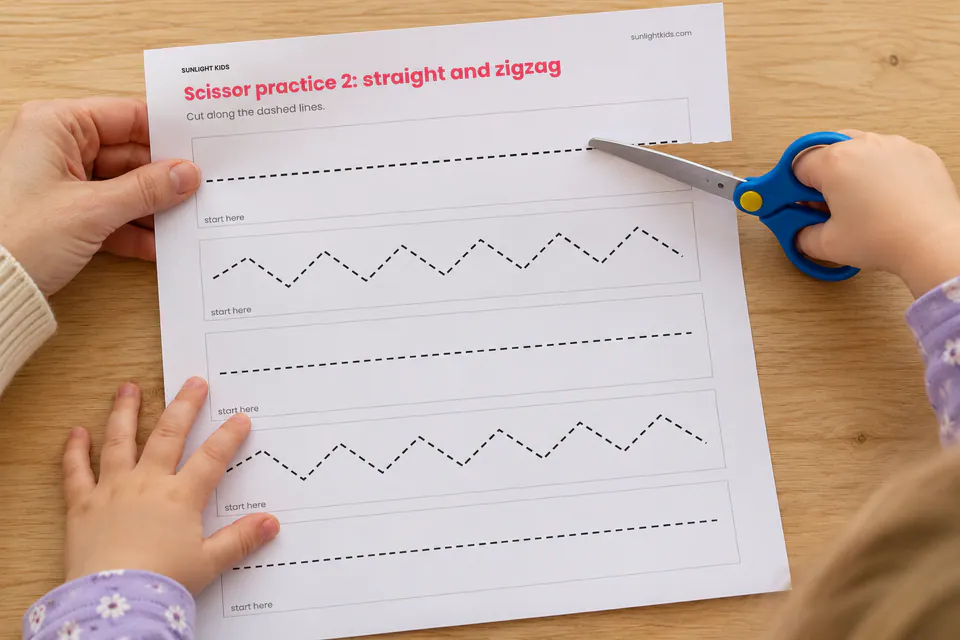 A child using blunt scissors on printed straight and zigzag practice lines.