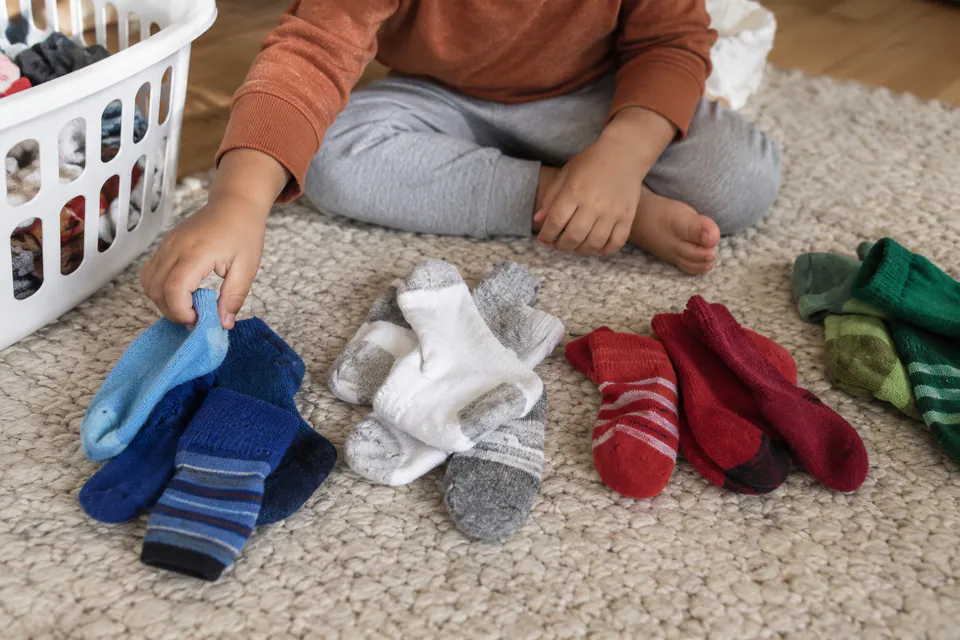 A child arranging matching pairs of colorful socks.