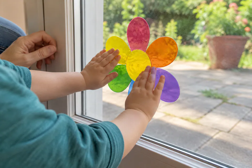 A child arranging translucent flower-shaped window clings on glass.