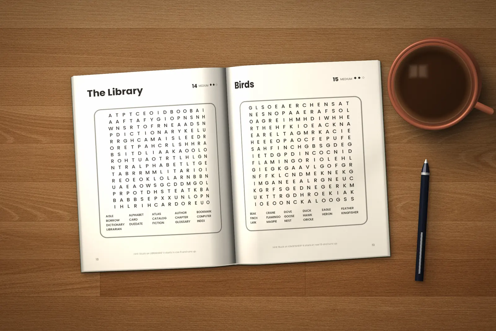 Word Search for Adults: Medium lying open on a wooden table, showing two word searches (“The Library” and “Birds”), next to a cup of coffee and a pen