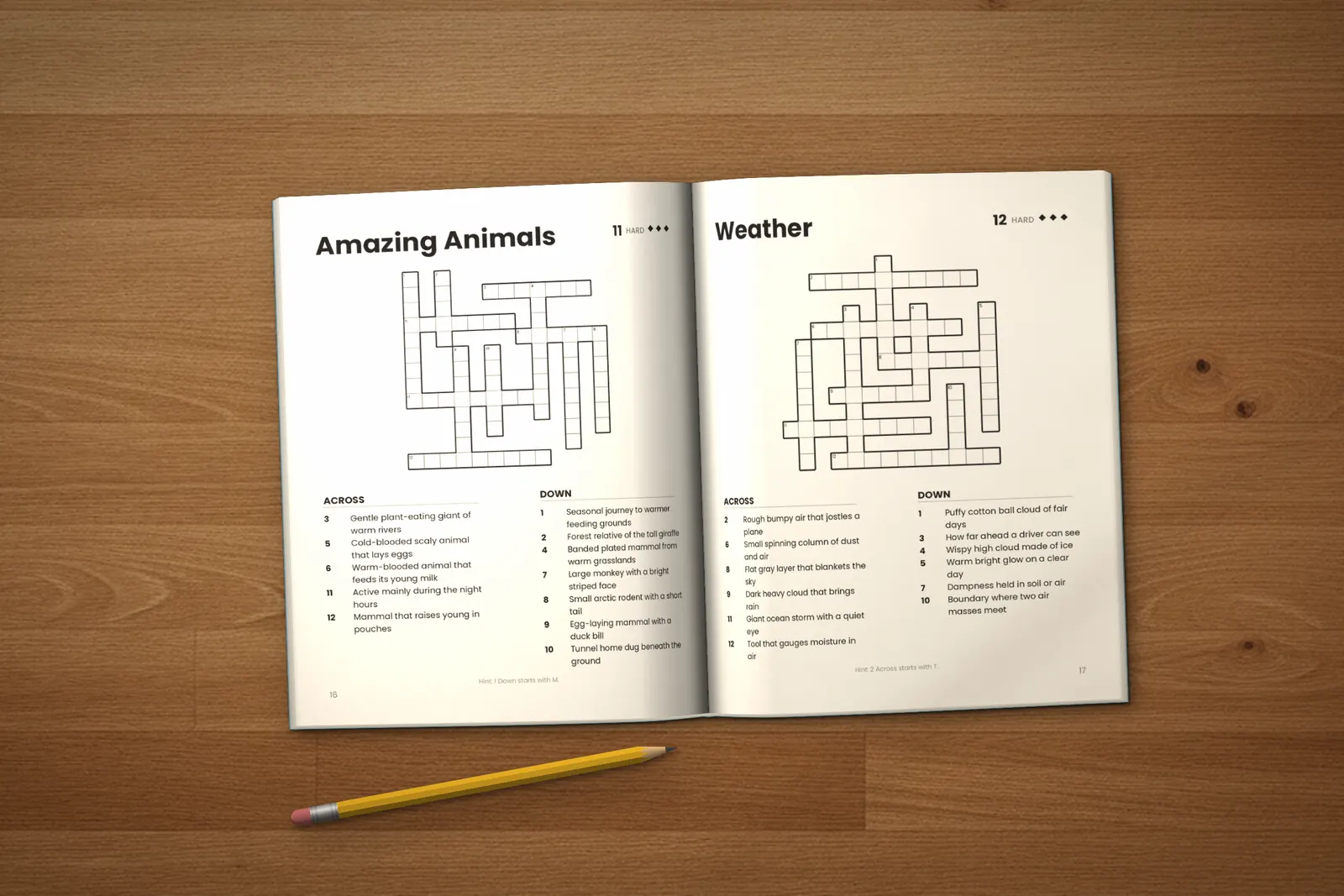 Crossword Puzzles for Kids: Hard lying open on a wooden table, showing two crosswords (“Amazing Animals” and “Weather”), next to a yellow pencil