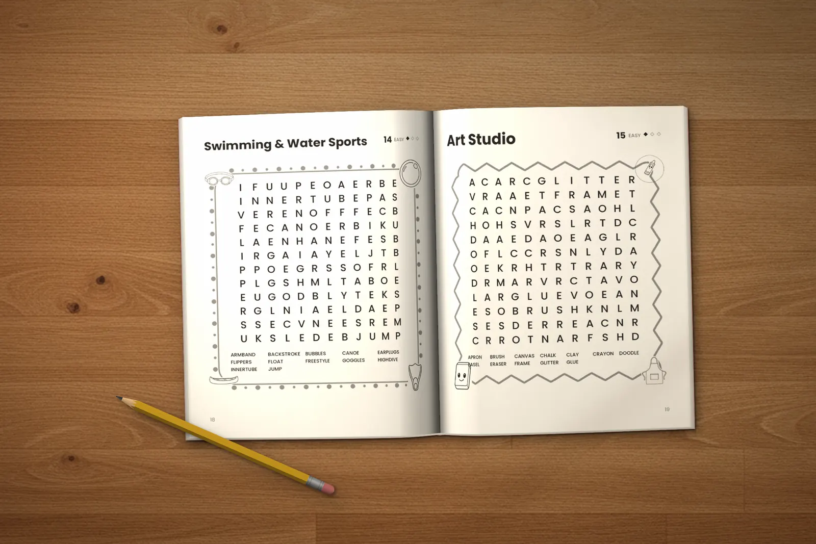 Word Search for Kids: Easy lying open on a wooden table, showing two word searches (“Swimming & Water Sports” and “Art Studio”), next to a yellow pencil