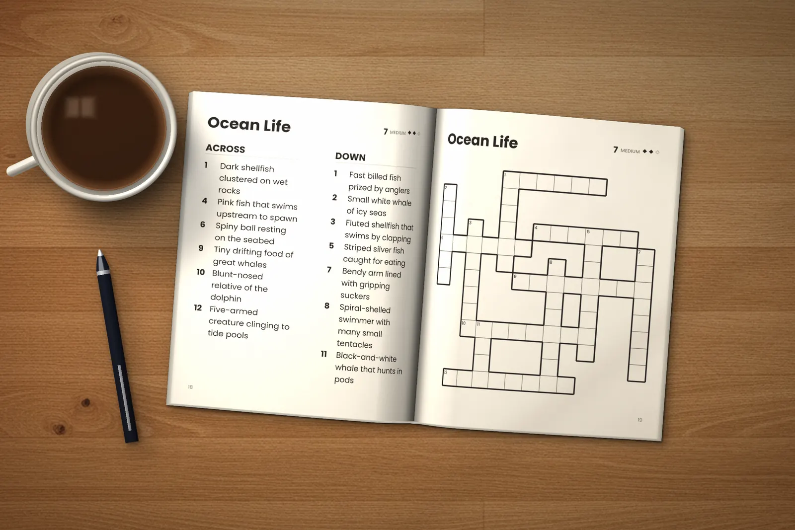 Large Print Crossword Puzzles for Seniors: Medium lying open on a wooden table, showing the clues and grid of the “Ocean Life” crossword, next to a cup of coffee and a pen