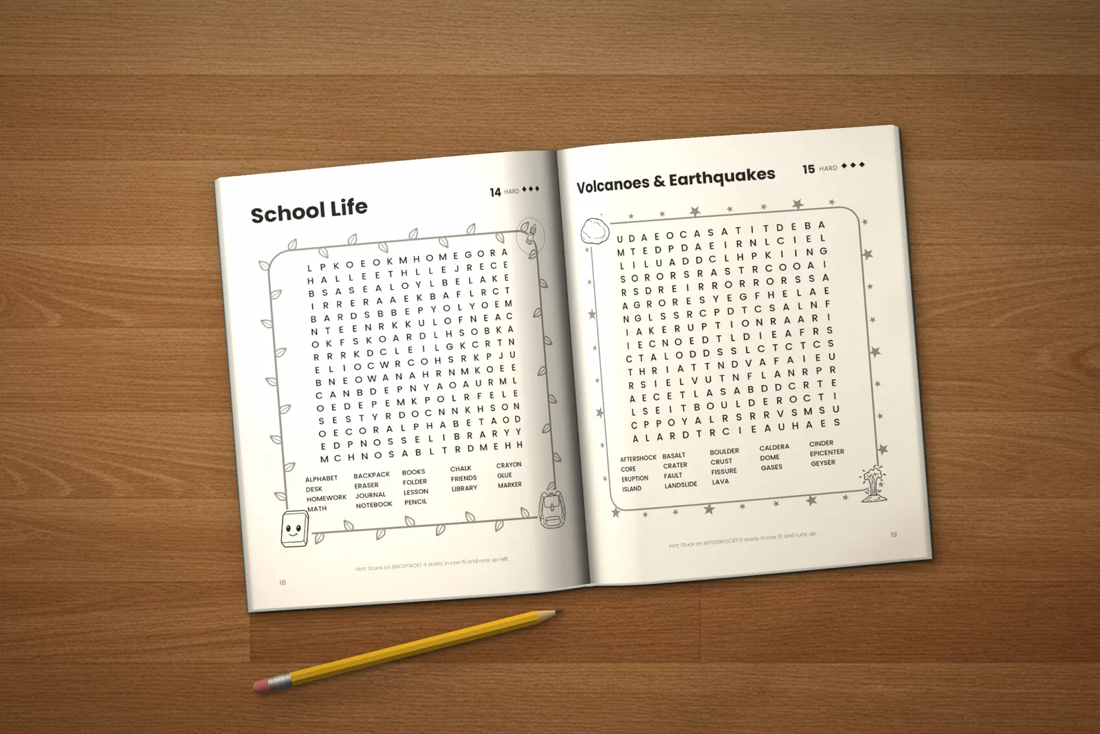 Hard Word Search for Teens lying open on a wooden table, showing two word searches (“School Life” and “Volcanoes & Earthquakes”), next to a yellow pencil